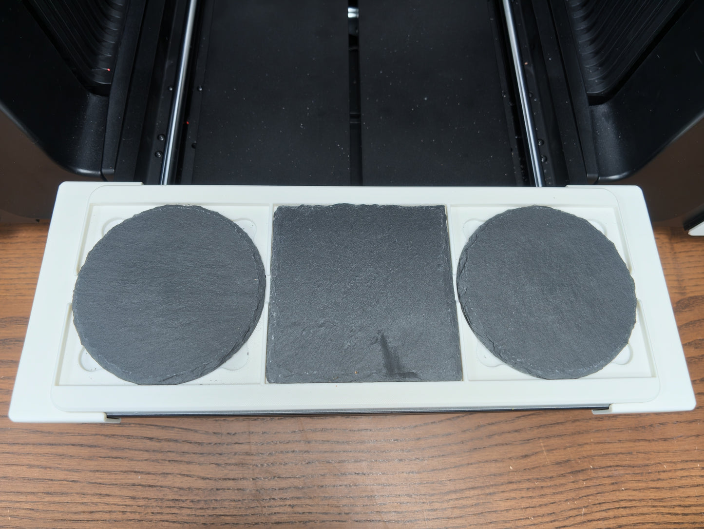 Slate coaster jig loaded with coasters on the xTool O1 Omni bed