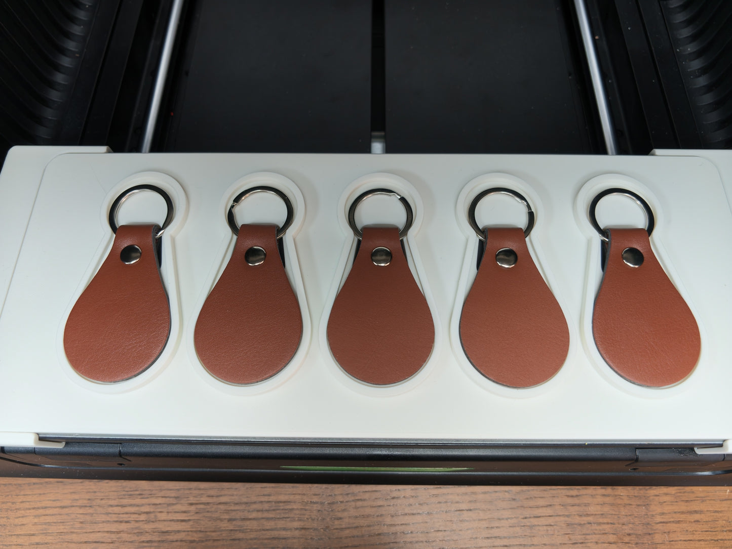 Leather keychain jig loaded with blanks ready for UV printing on the xTool O1 Omni