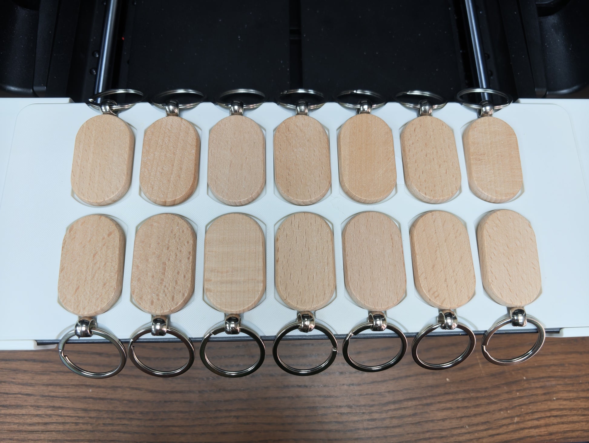 Oval wooden keychain jig loaded with blanks ready for UV printing on the xTool O1 Omni