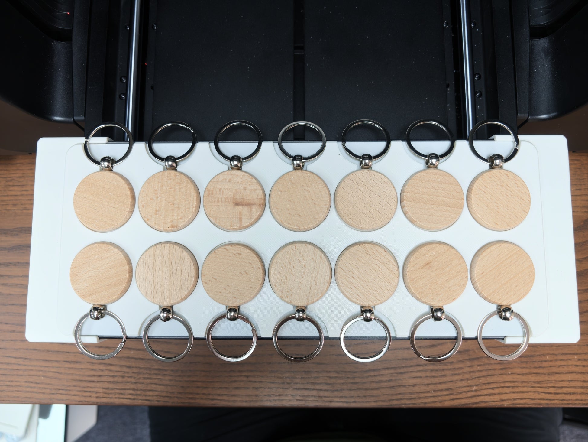 Round wooden keychain jig loaded with blanks on the xTool O1 Omni bed