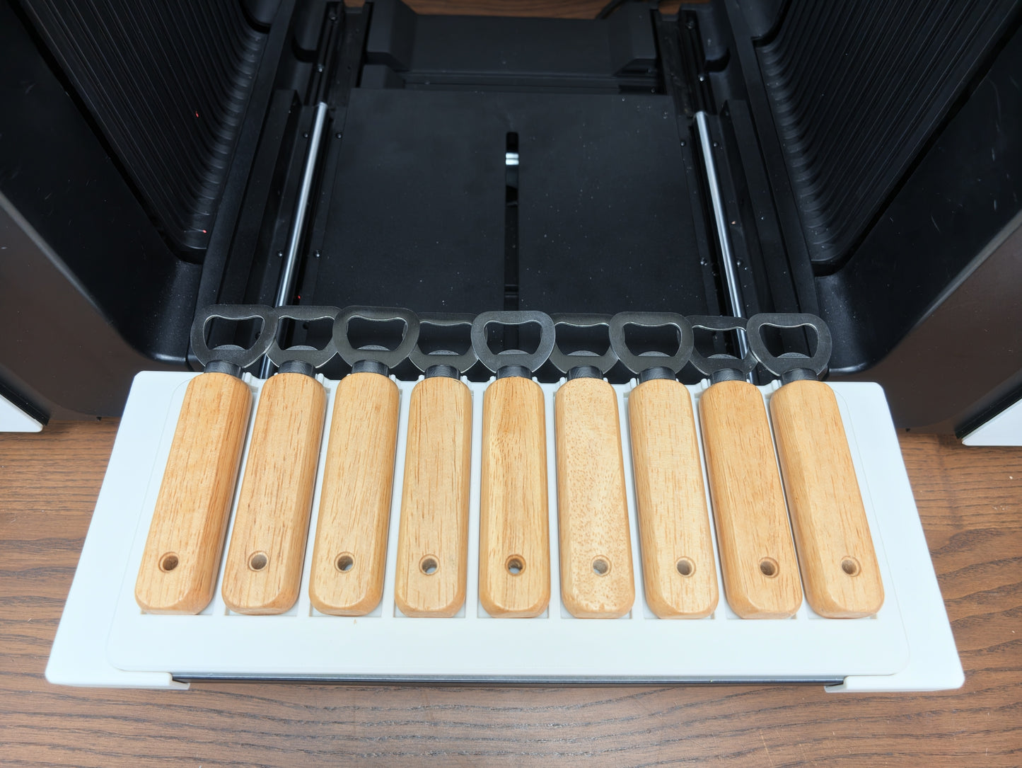 Wooden bottle opener jig loaded with blanks on the xTool O1 Omni bed