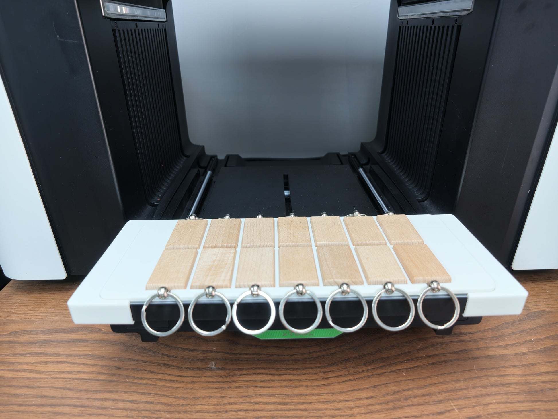 Angled view of the matte white rectangular keychain jig for the xTool O1 Omni UV printer