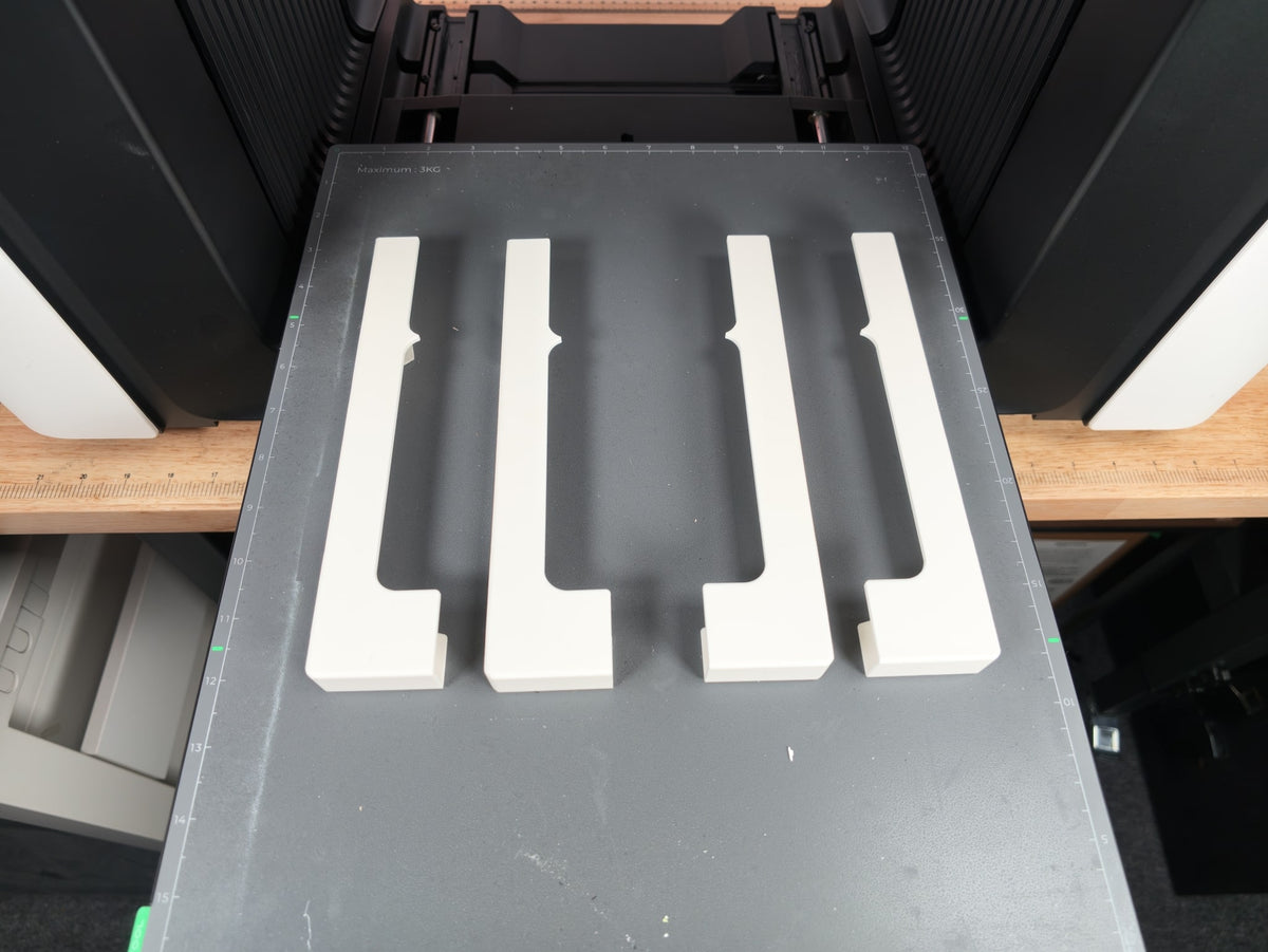 The four Omni Bracket System XL brackets, two mirrored pairs, on the xTool O1 Omni baseplate